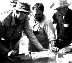 photo of Archeologist Mike Collins examining a collection brought to the McFaddin Beach conference with Dennis Stanford and Russell Long